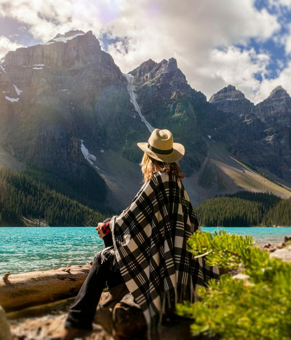 Mature woman meditating peacefully outdoors near a lake.